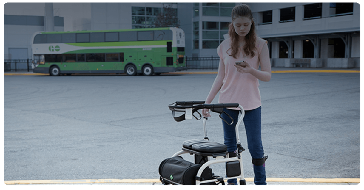 A rider with a walker checks a phone in a GO bus loop