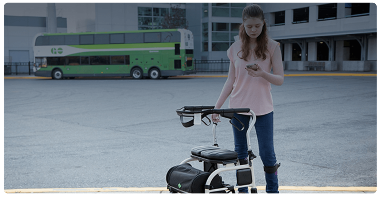 A rider with a walker checks a phone in a GO bus loop