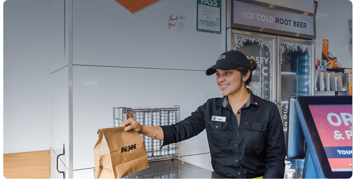 An A&W staff member hands over a takeout bag