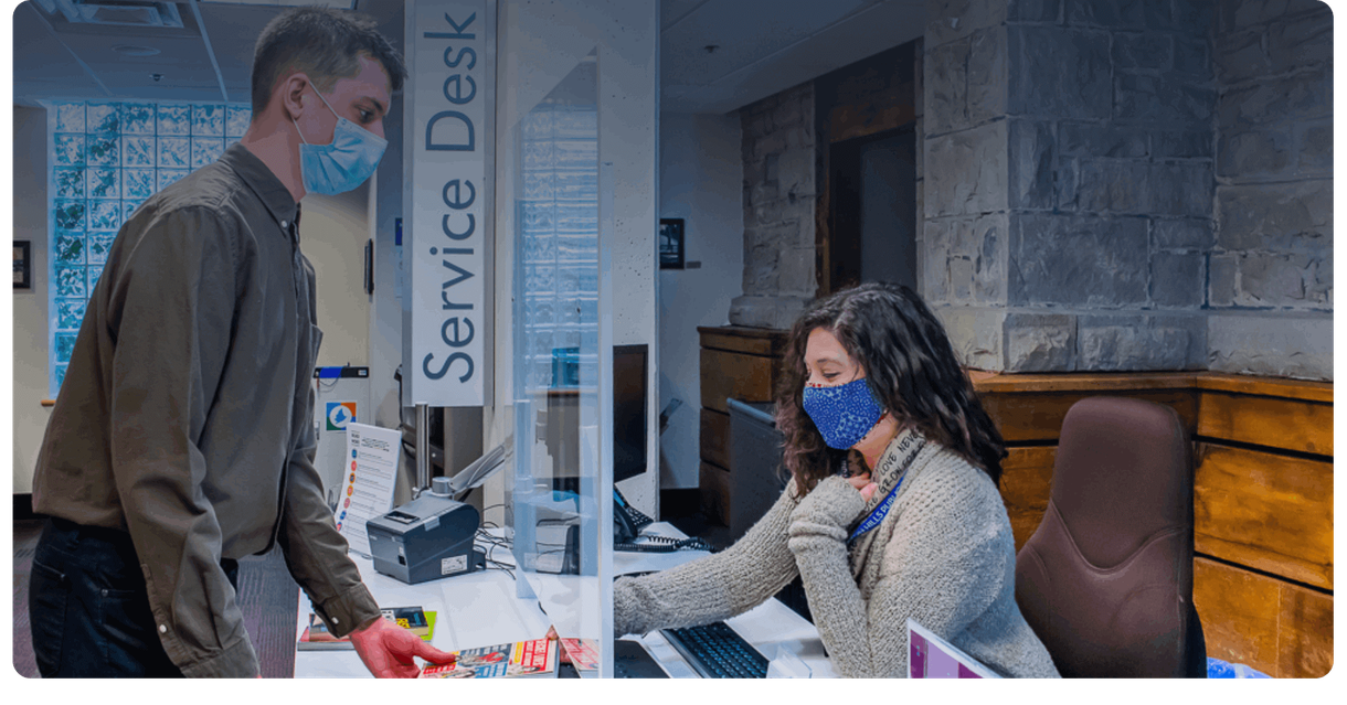 A visitor at the library service desk with a staff member