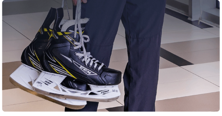 A person carries a pair of hockey skates