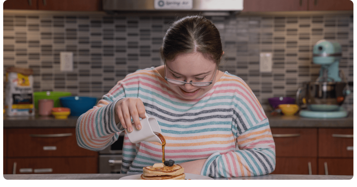 A baker pours syrup over a stack of pancakes