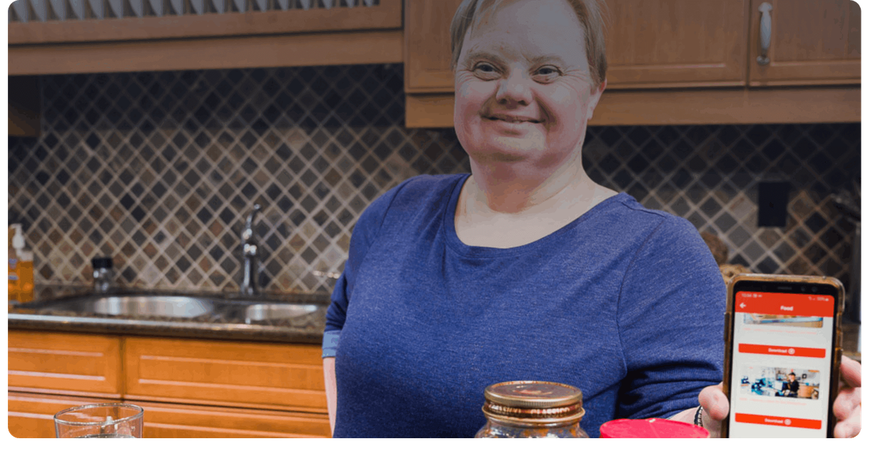 A cook in a kitchen holds up a phone showing MagnusCards