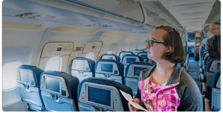 A passenger holding a boarding pass stands in an airplane aisle