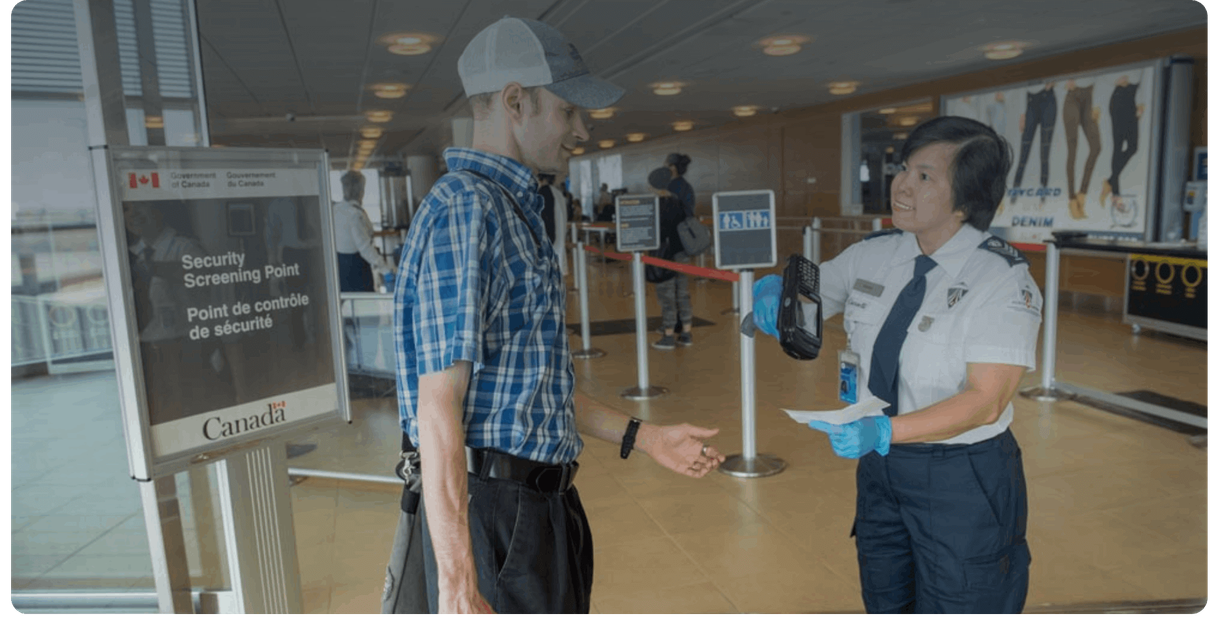 A security officer checks a traveller’s boarding pass