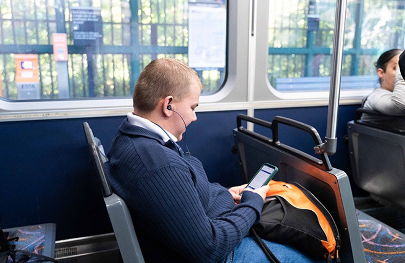 A rider looks at a phone while seated on an NJ Transit light rail train