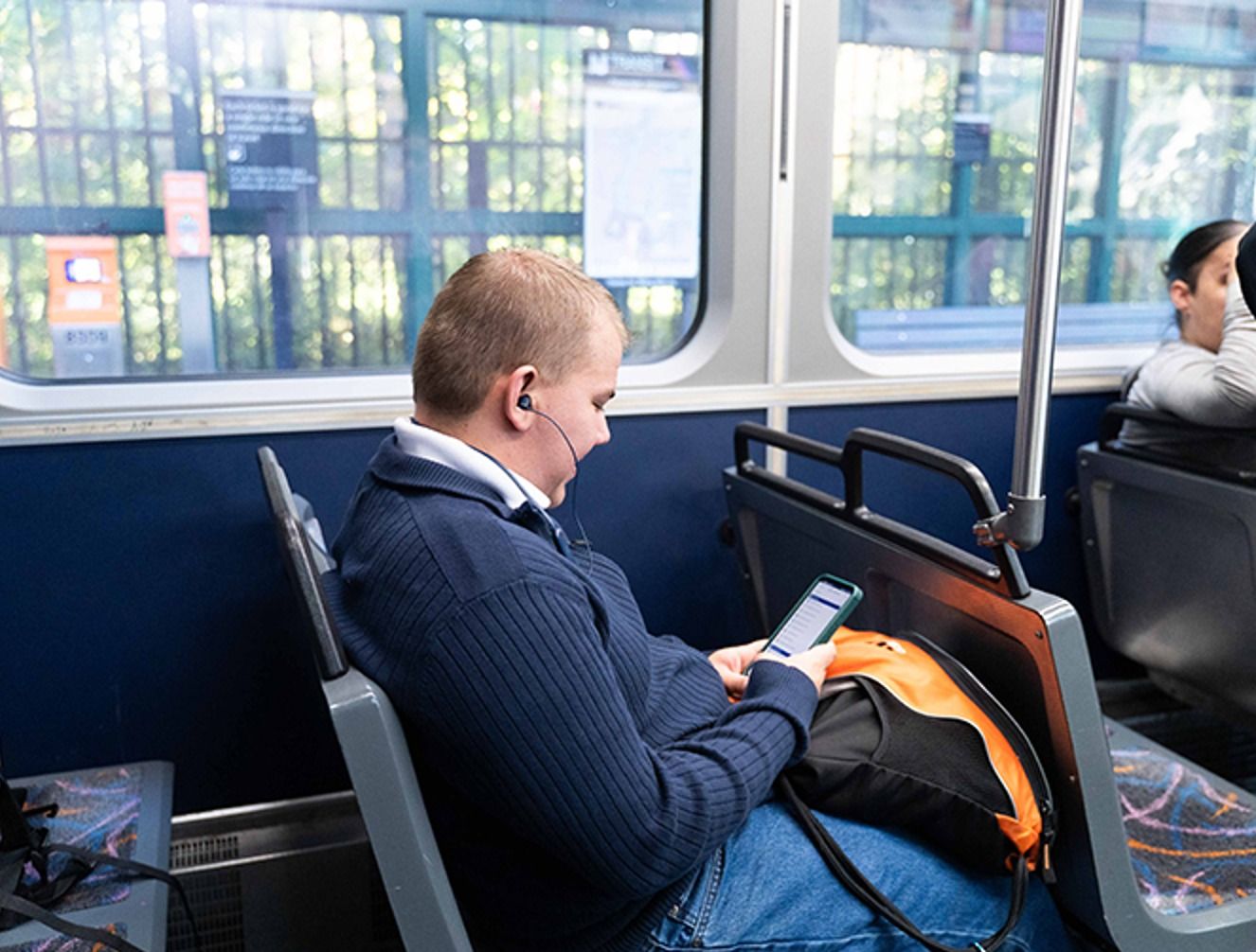 A rider looks at a phone while seated on an NJ Transit light rail train