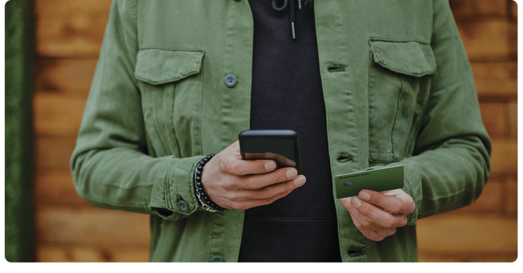 A customer holds a phone and a green debit card