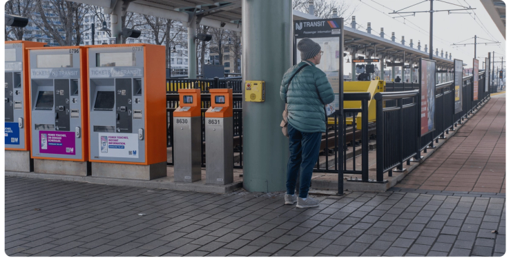 A rider reads the information sign beside the light rail ticket machines