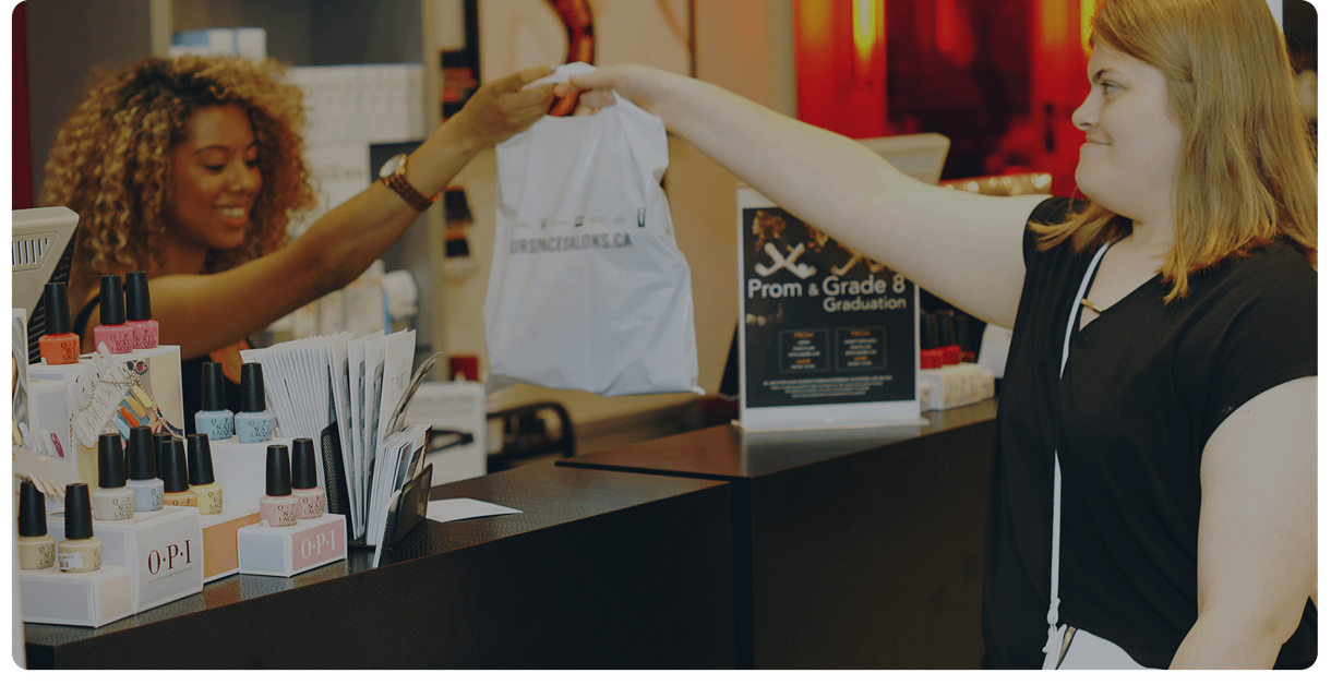 A cashier hands a customer her purchase at a store counter