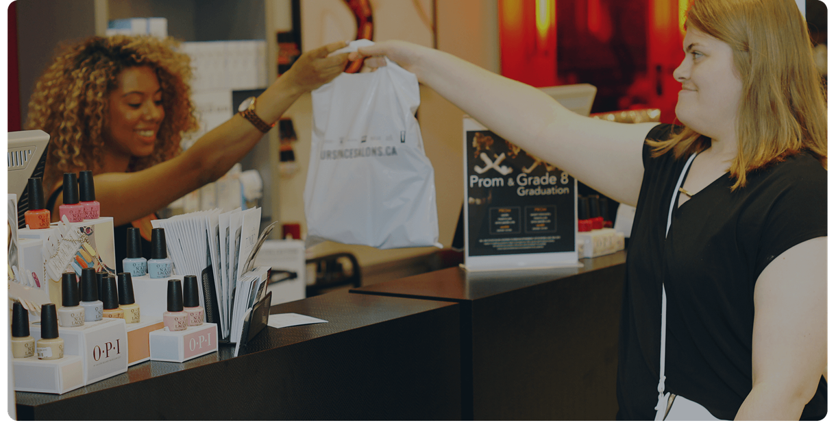 A cashier hands a customer her purchase at a store counter