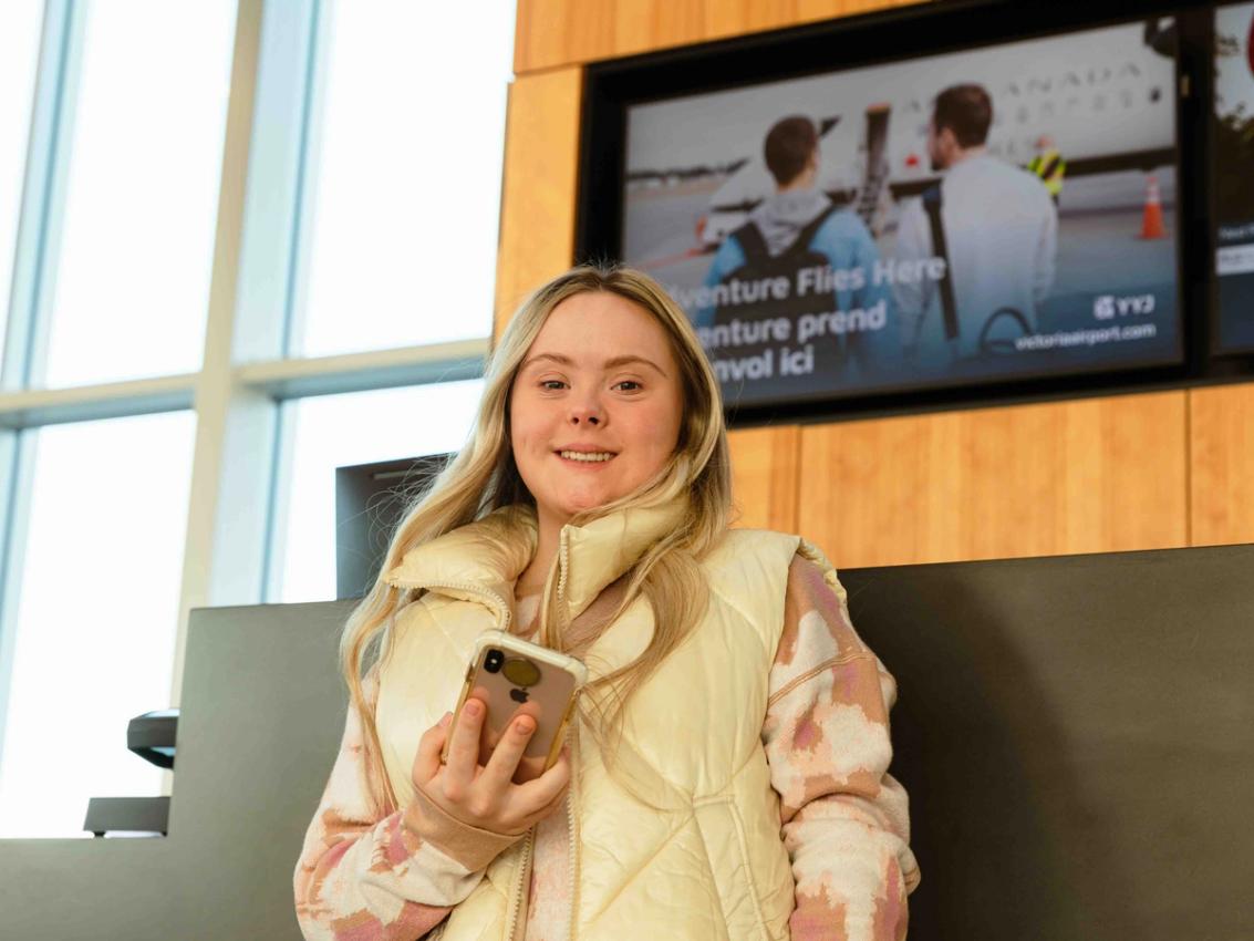 A traveller holds up a phone at Victoria International Airport