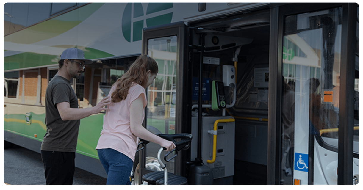 A rider with a walker boards a GO bus with help from another passenger
