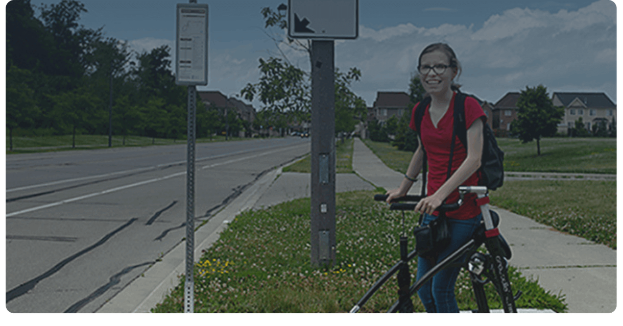 A rider with a walker waits at a Milton Transit bus stop