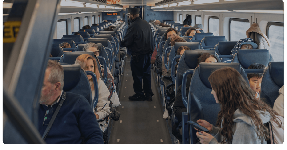 Riders in their seats as a conductor walks the aisle of an NJ TRANSIT train