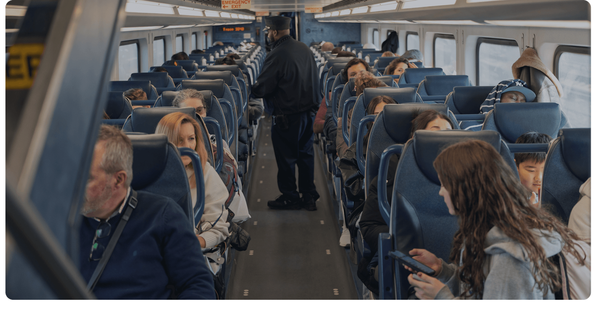 Riders in their seats as a conductor walks the aisle of an NJ TRANSIT train