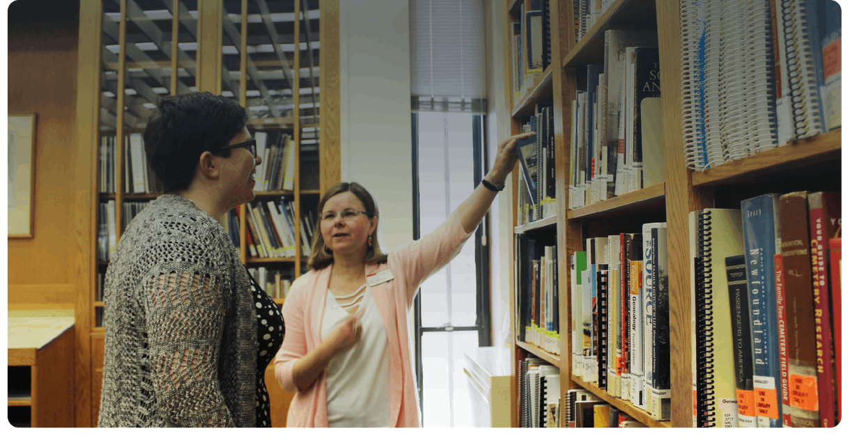 A staff member points to a shelf for a visitor