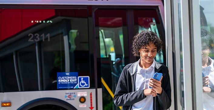 A rider looks at a phone while stepping off a COTA bus