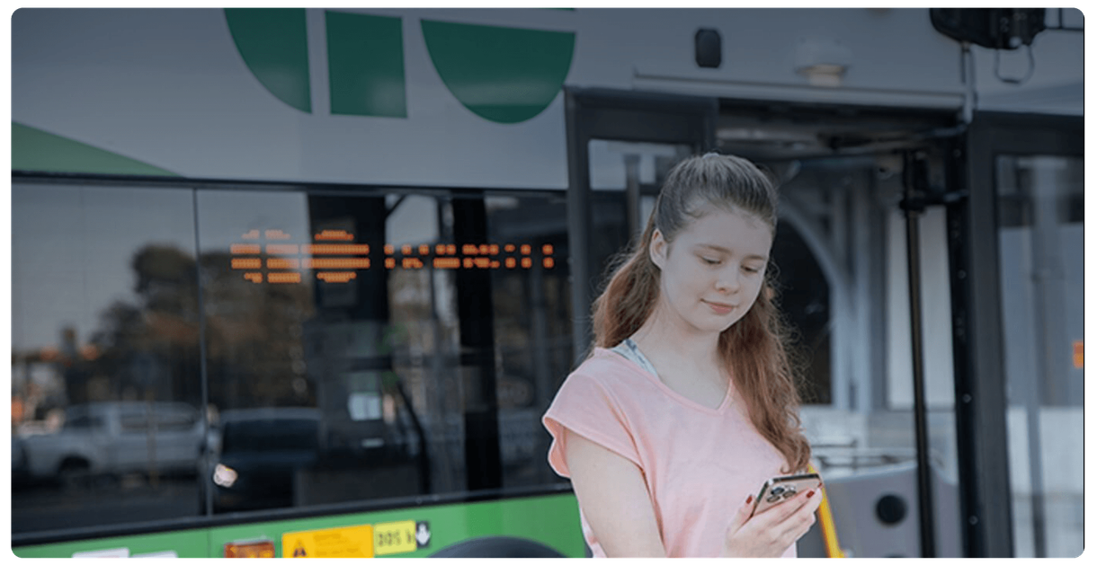 A rider uses a phone beside a GO bus