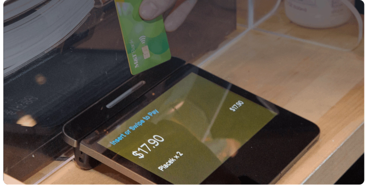 A debit card held over a payment terminal