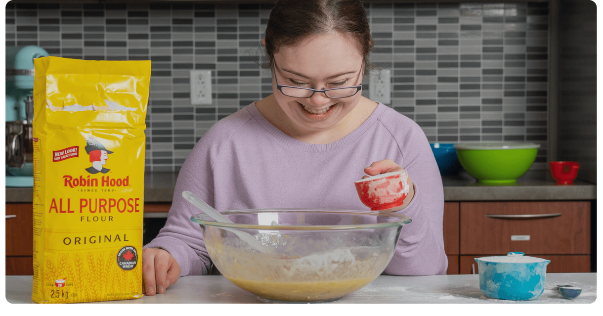 A baker mixes banana bread batter beside a bag of Robin Hood flour