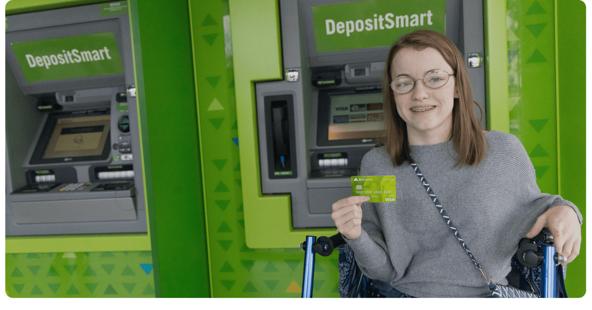 A customer holds her Regions debit card at a Regions ATM