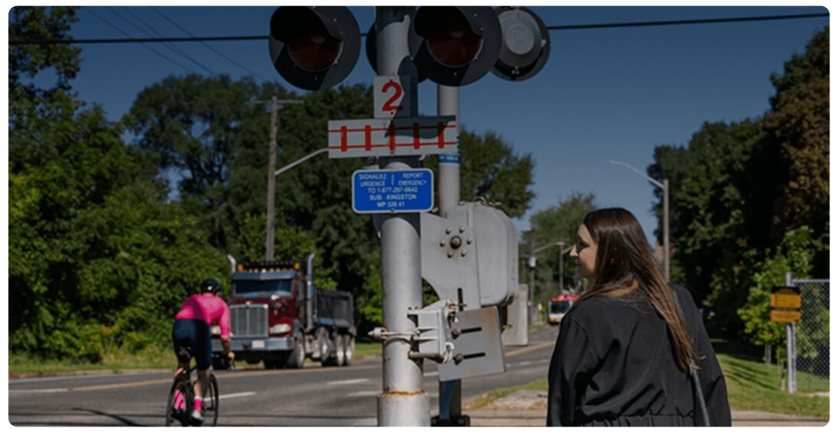A pedestrian and a cyclist at a rail crossing