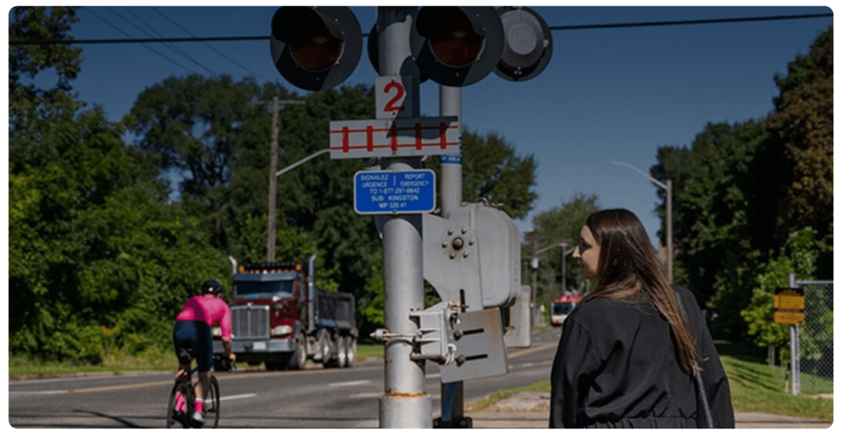 A pedestrian and a cyclist at a rail crossing
