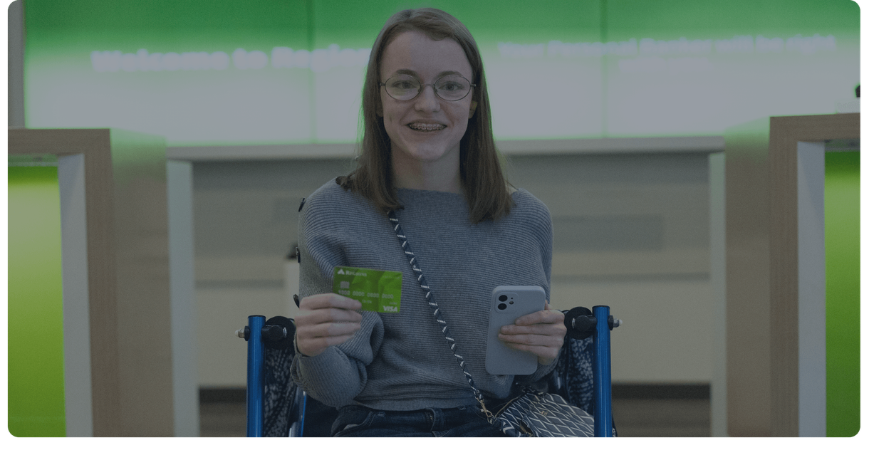A customer holds up her Regions debit card and her phone in a branch