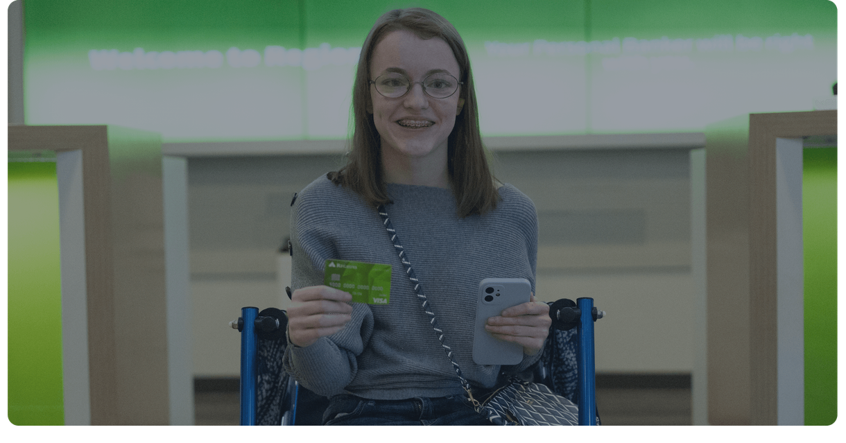 A customer holds up her Regions debit card and her phone in a branch
