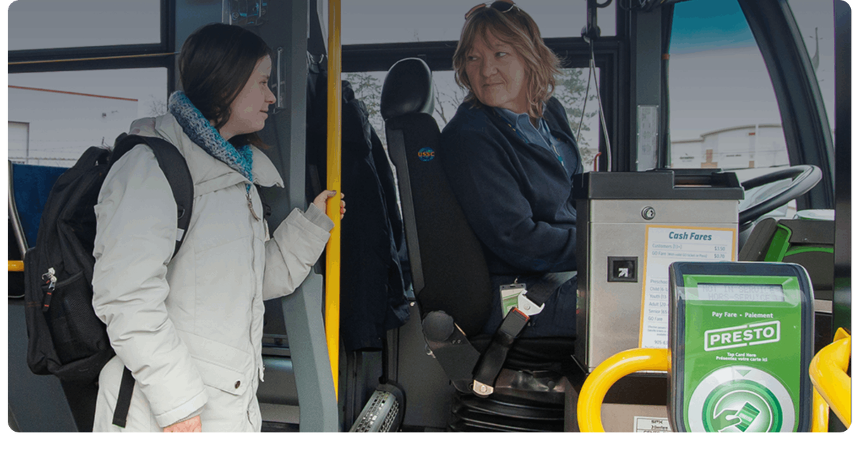A rider holds a pole and talks with the driver on a Burlington Transit bus