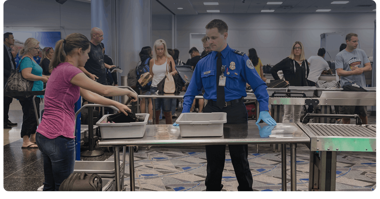 Travellers put their bags in bins at airport security
