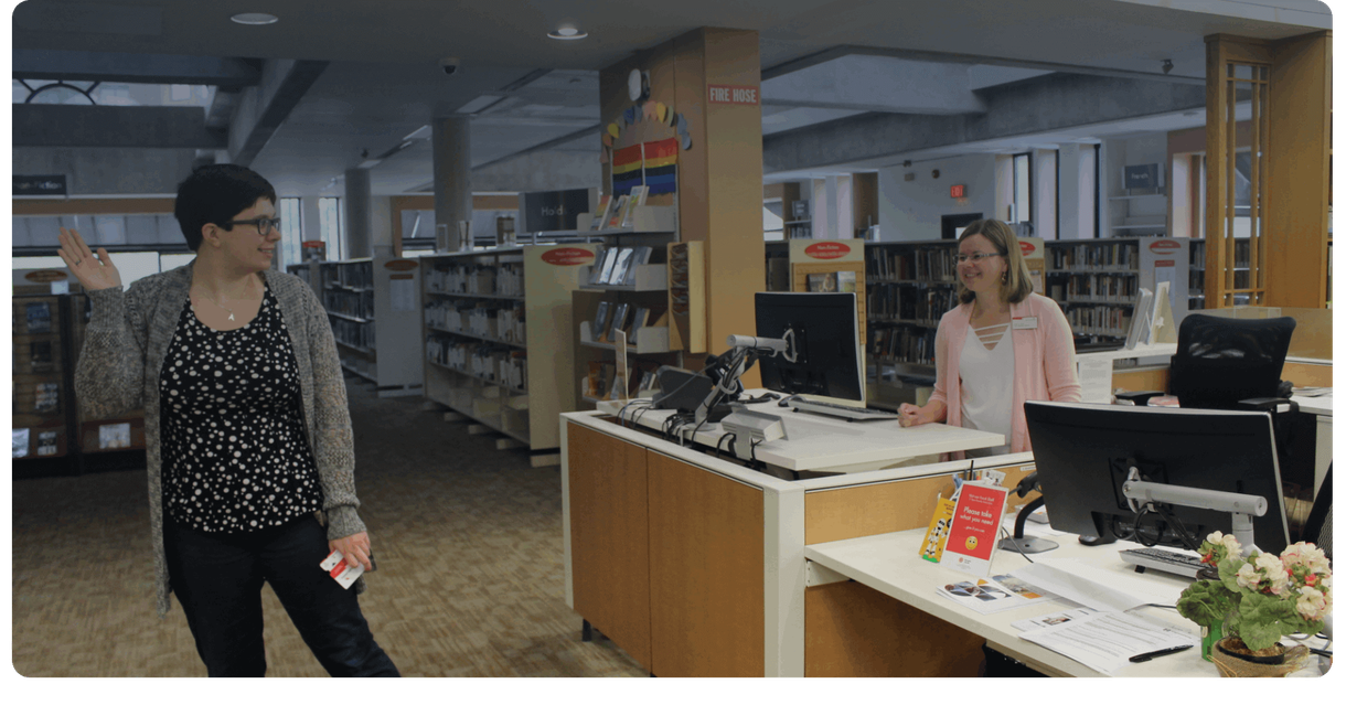 A visitor holds a library card at the service desk