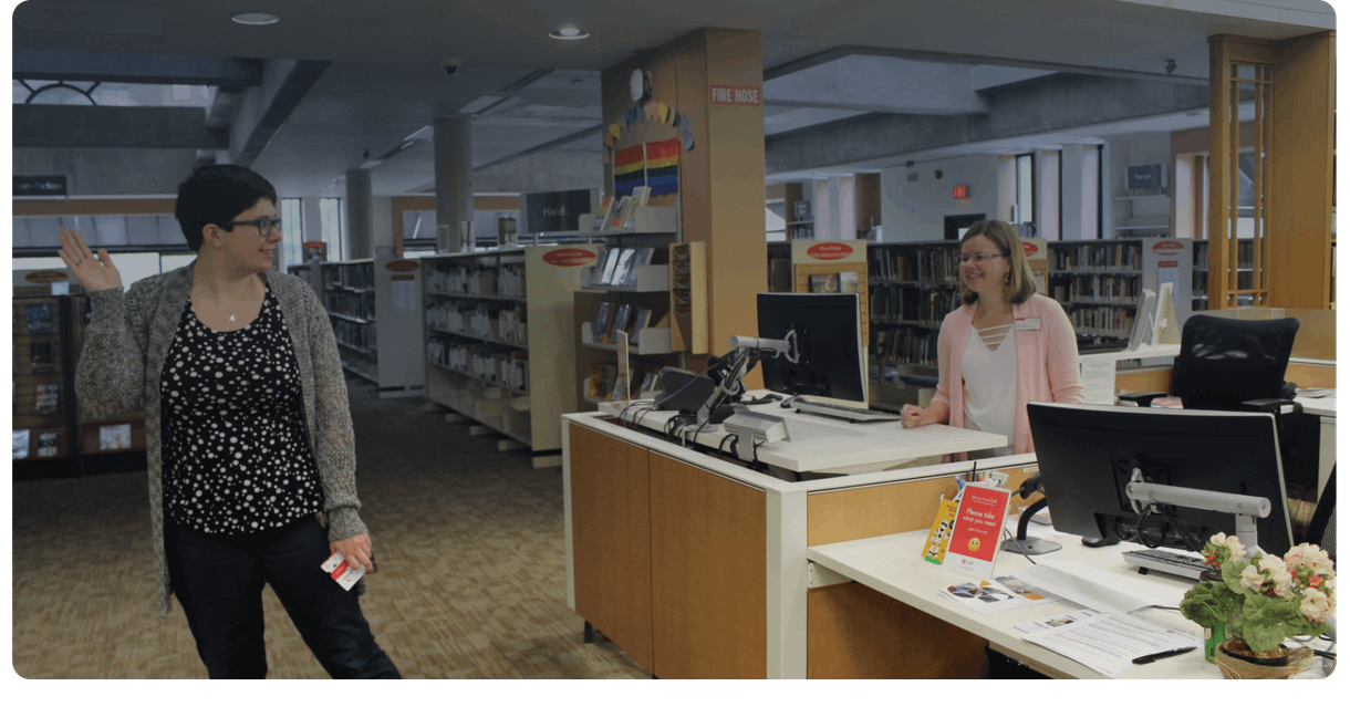A visitor holds a library card at the service desk
