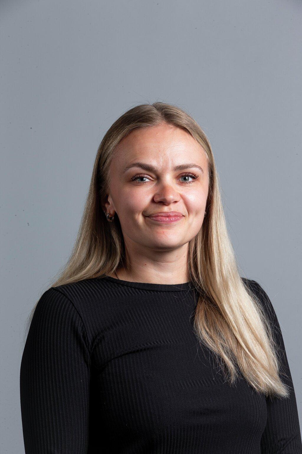 the woman is wearing a black shirt and smiling for the camera .