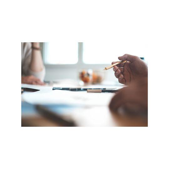 a person is holding a pen in their hand while sitting at a table .