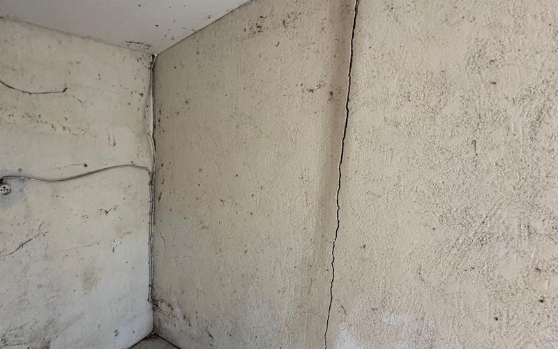 Fissure verticale sur un mur intérieur d'une maison ancienne, signe de fragilisation structurelle à réparer en maçonnerie