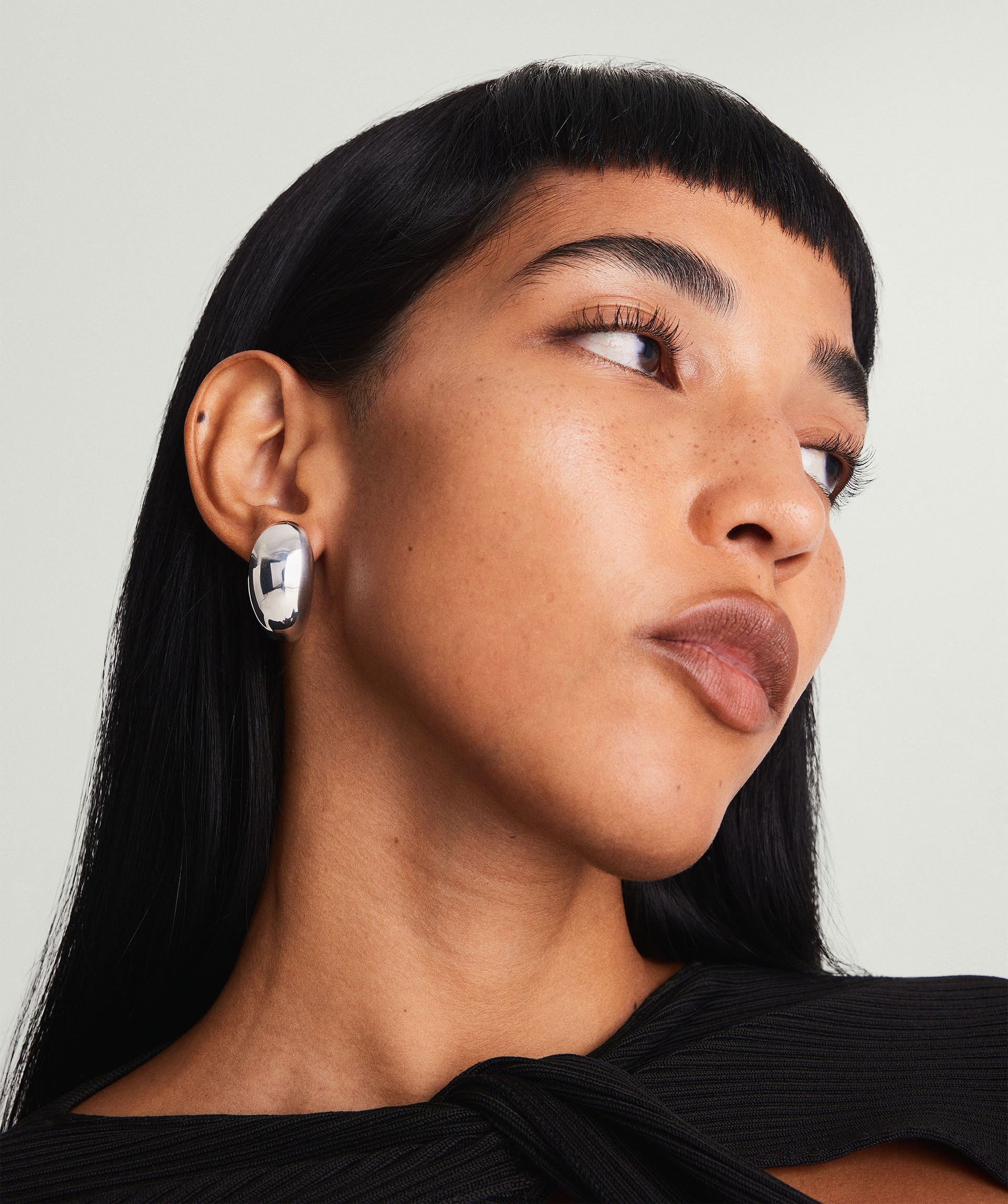 A model wearing the Mega Dome Earrings in silver