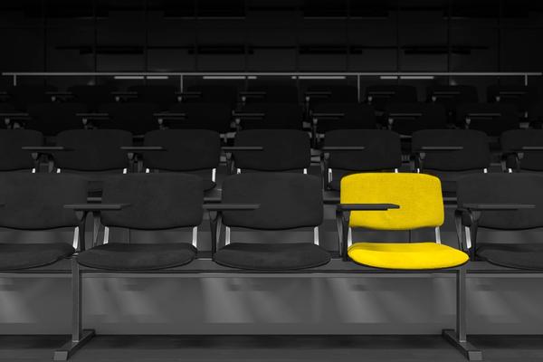A single yellow seat standing out in rows of dark lecture-theatre seating