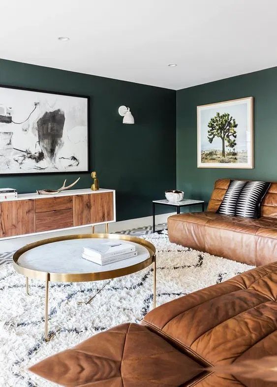 A moody living room with a dark green accent wall, leather sofa, and a stylish modern interior design.