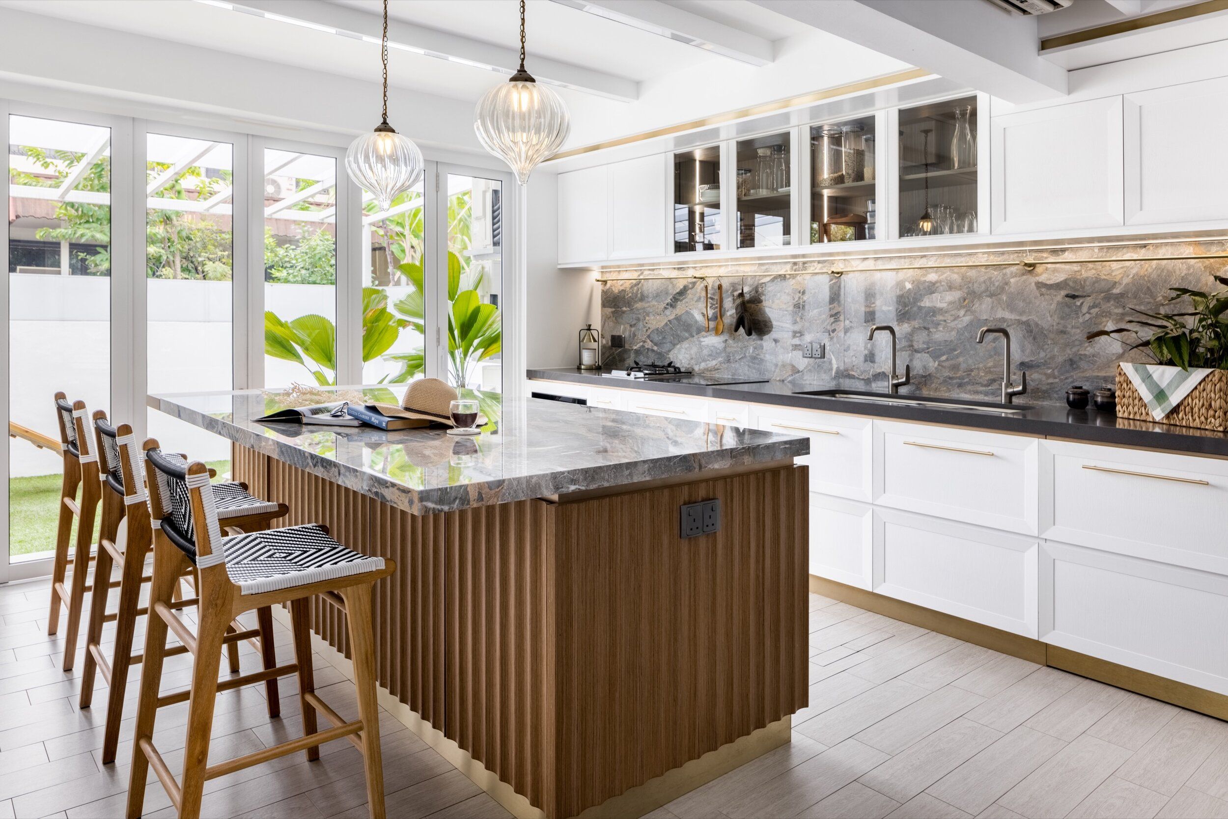 A kitchen featuring a wood-clad kitchen island with marble countertops, pendant lighting, and sleek cabinetry, combining vintage wood elements with modern finishes.