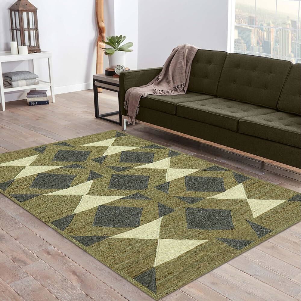 A geometric-patterned flat weave rug in green and beige tones placed in a modern living room with a dark green sofa.