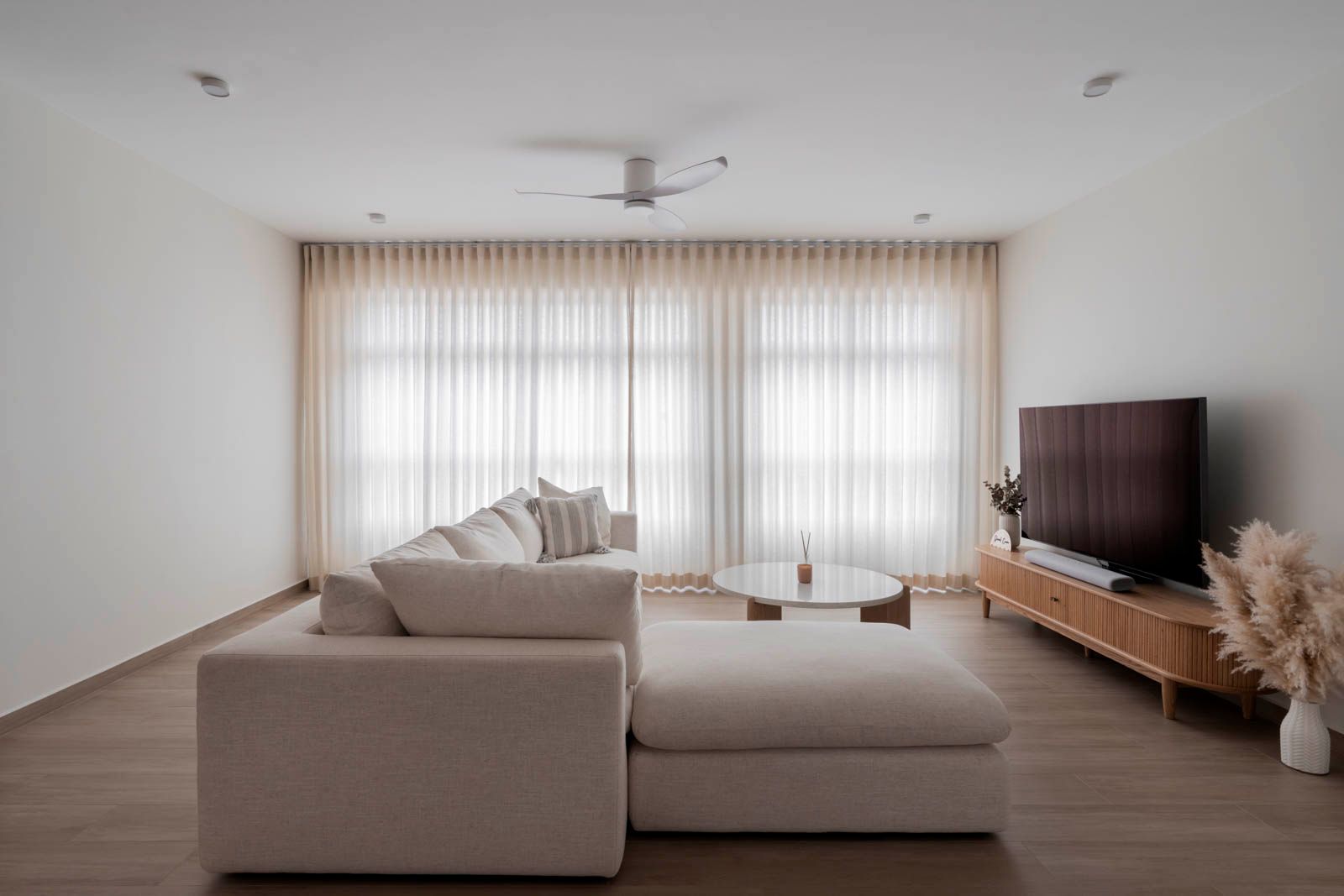 Scandinavian living room designed by Lemonfridge Studio featuring a white sofa, wooden coffee table, and abundant natural light through large windows.