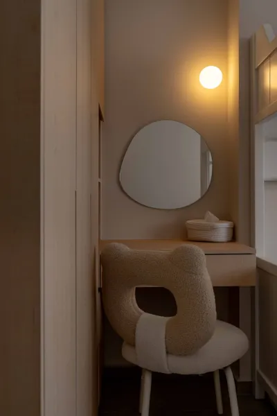 Vanity space with asymmetrical round mirror lit up by a warm bulb