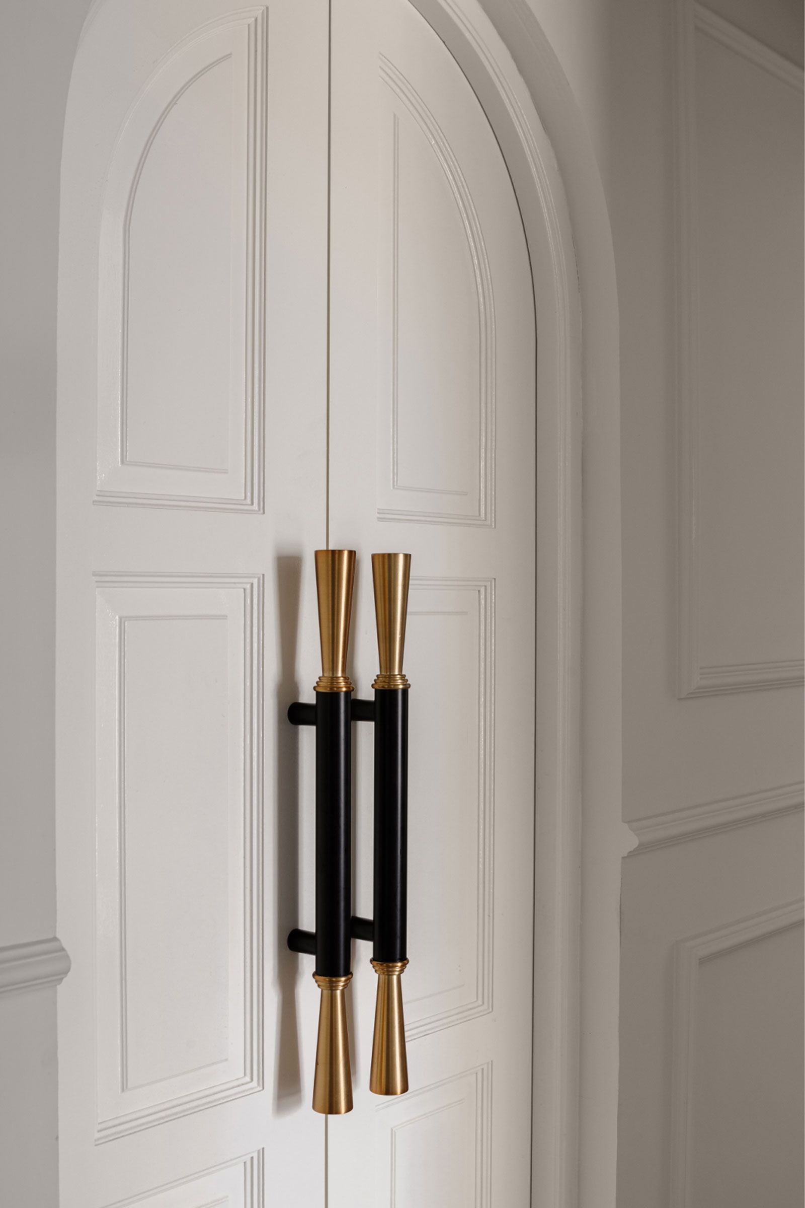 Close-up of a white double door with elegant gold and black handles.