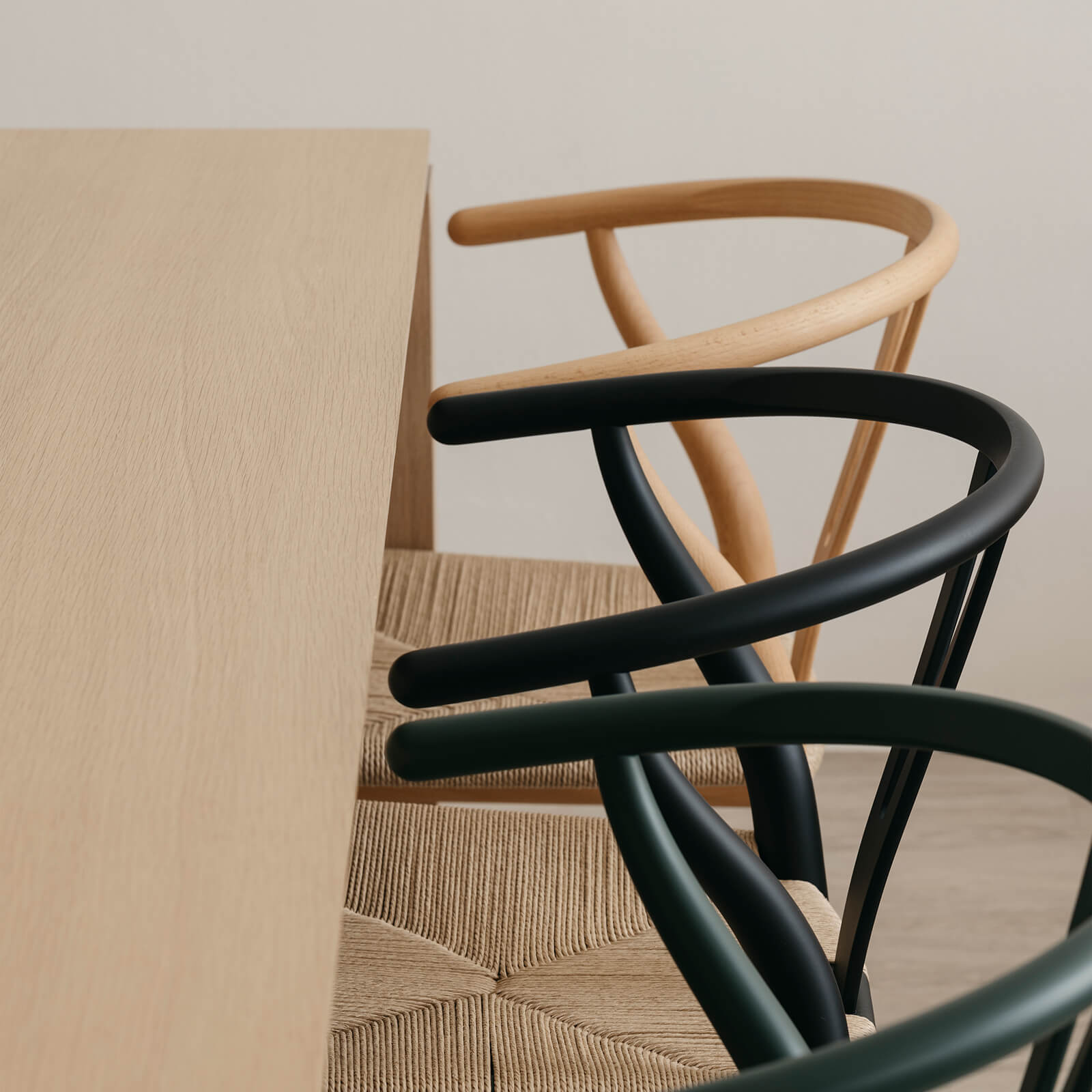 Close-up of modern dining chairs and wooden table in a minimalist dining room, featuring iconic Wishbone Chairs.