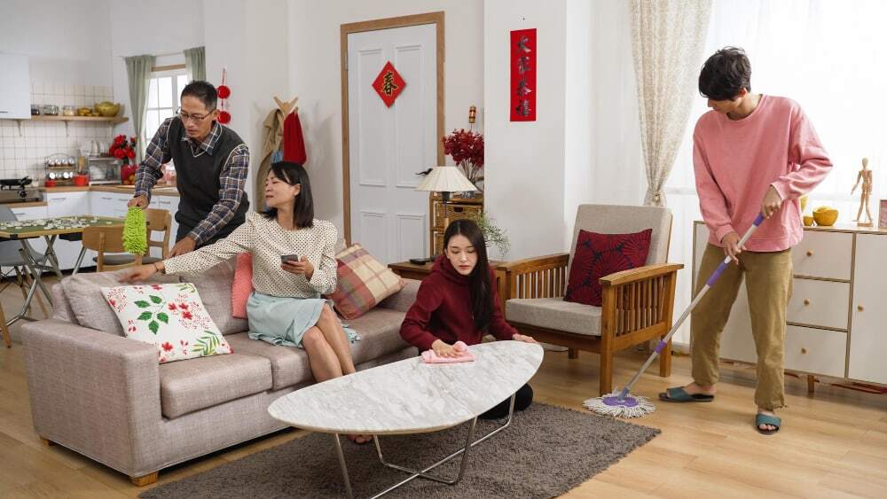 Family members teaming up to clean and declutter their living room in preparation for Chinese New Year