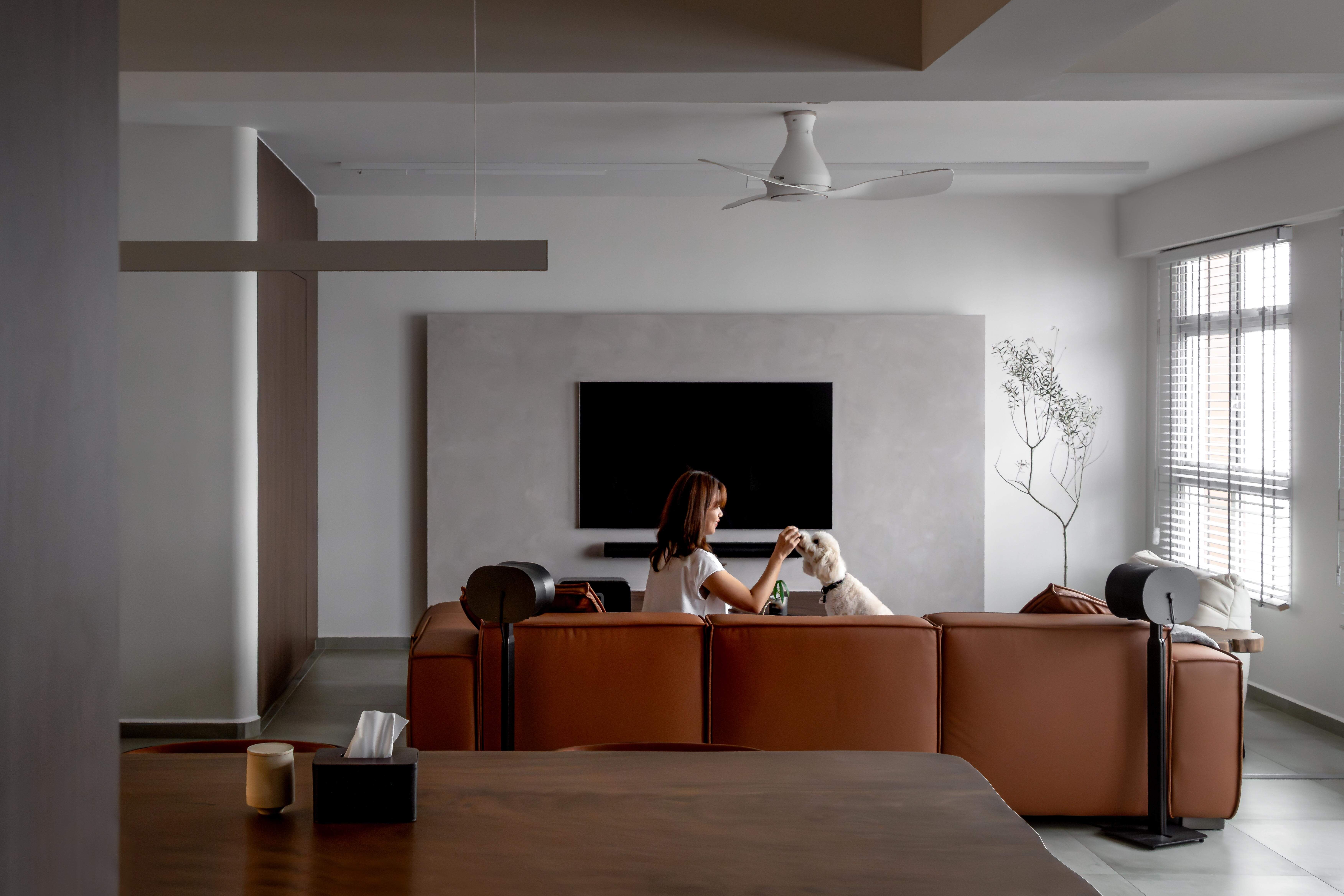 Modern living room with a cozy sofa, a dog, and a clean minimalist design featuring soft lighting and muted tones.