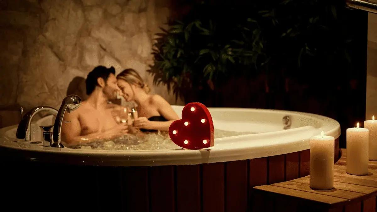 Couple relaxing in an intimate hot tub surrounded by soft candlelight.