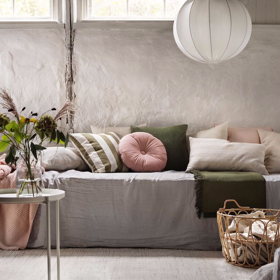 Stylish living room featuring a Peach Fuzz-colored round cushion by IKEA, complemented by a chic assortment of throw pillows